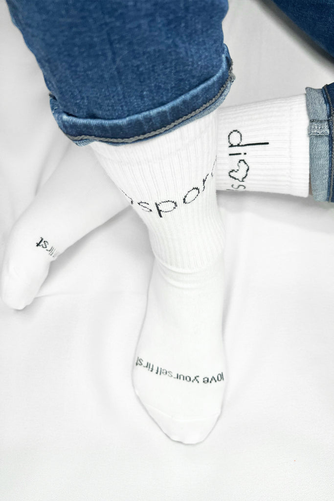 "Love yourself first" reliable everyday sock Diaspora unisex solids ribbed crew socks are steady as they come. Expertly crafted with lush soft cotton available in black, this sock is an essential. Classic crew sock for all of life's occasions. Black and white knitting. Soft 97% Cotton 3% Elastane